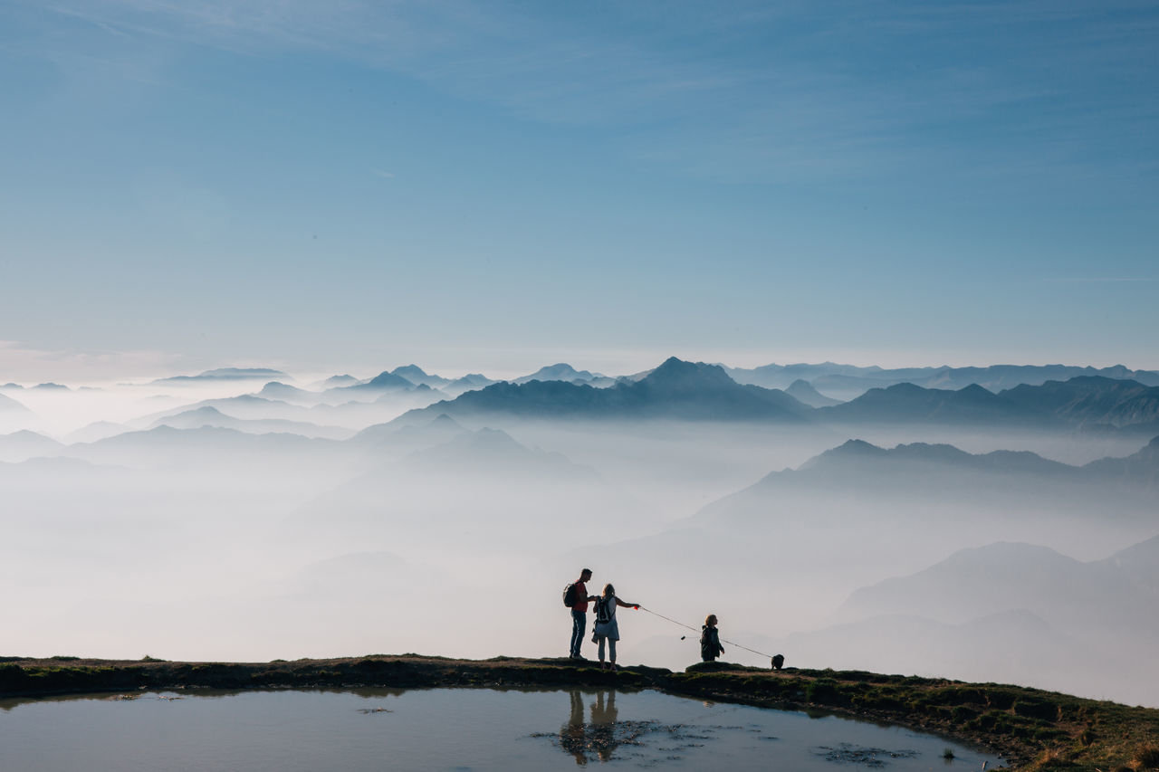 mountain, scenics - nature, sky, beauty in nature, water, real people, mountain range, tranquility, tranquil scene, leisure activity, lifestyles, lake, nature, standing, non-urban scene, men, two people, people, idyllic, outdoors