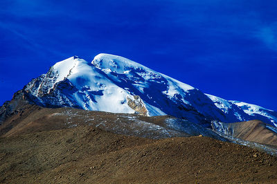 Snow covered mountain against blue sky