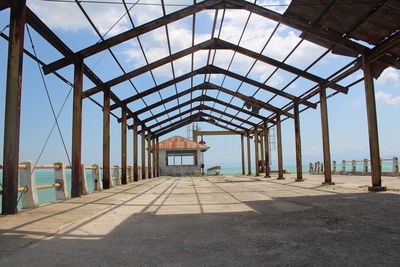 Empty walkway in building against sky