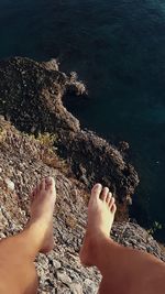 Low section of woman on rock at beach