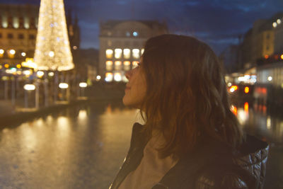 Side view of thoughtful woman looking away in illuminated city at night