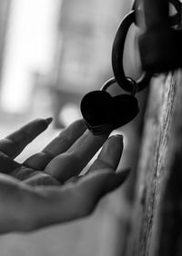 Close-up of hand holding heart shape padlock on door