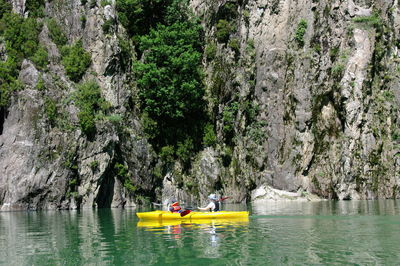 Man kayaking in lake against cliff