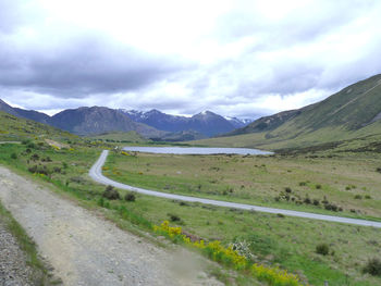 Scenic view of road by mountains against sky