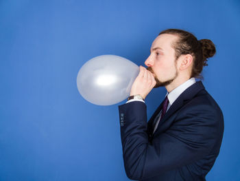 Midsection of man with balloons against blue background