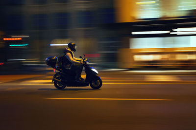 Man riding motorcycle on street at night