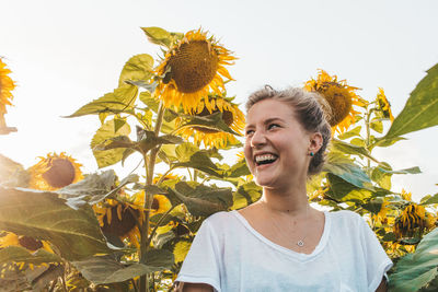 Happy beautiful young woman standing at sunflower field