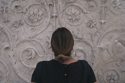 Rear view of woman standing against wall