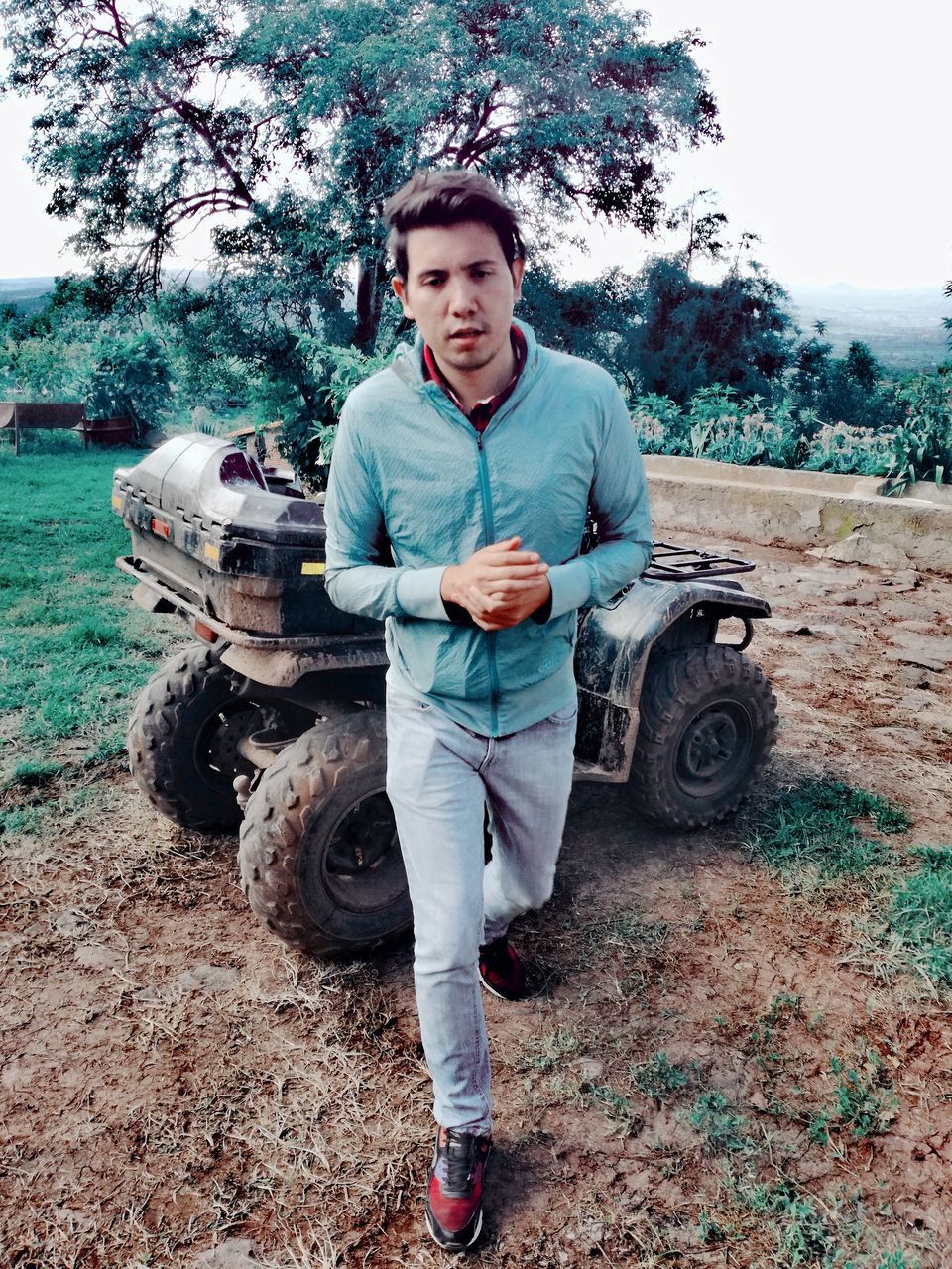 one person, young men, portrait, young adult, front view, transportation, mode of transportation, real people, looking at camera, leisure activity, plant, full length, nature, casual clothing, lifestyles, land, day, tree, men, outdoors, tire, wheel