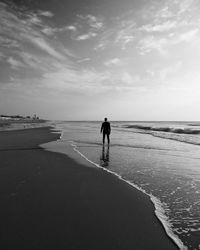 Rear view of man standing on shore at beach