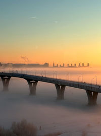 Yakhtenniy bridge over the great nevka river against sky during sunset in winter