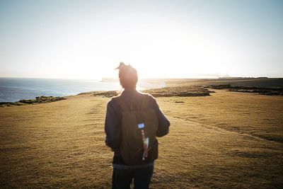 Rear view of man standing on beach against clear sky