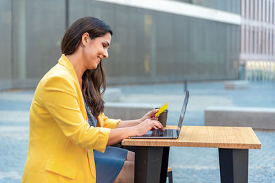 Caucasian mid adult businesswoman paying with card in computer