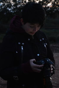 Young woman holding camera outdoors