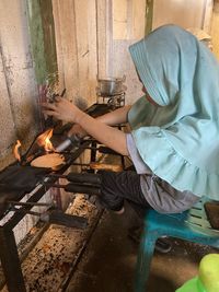 Side view of woman cooking food in kitchen