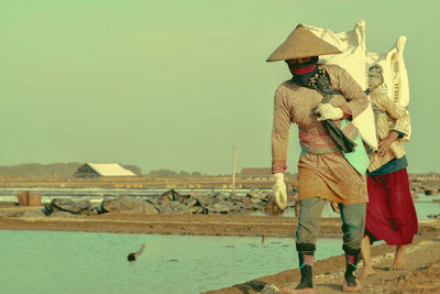 Full length of man and woman walking at salt flat against sky