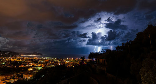 Lightning storm over sea by townscape at night at chiavari