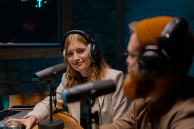 A man and a woman are sitting in front of microphones in a studio. podcast studio concept