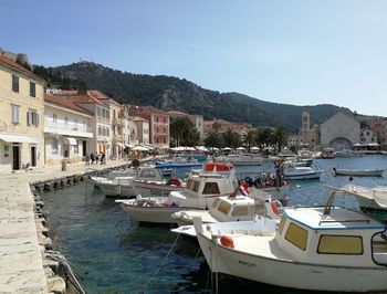 Sailboats moored on sea by buildings in city against clear sky