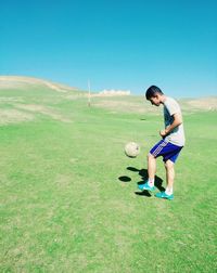 Full length of woman playing soccer ball on grass