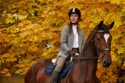 Portrait of young woman riding horse on field