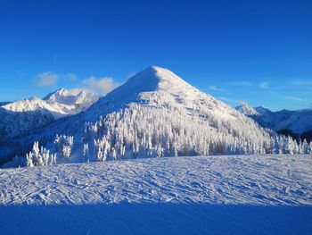 Scenic view of snowcapped mountains against blue sky