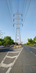 Electricity pylon by road against clear sky