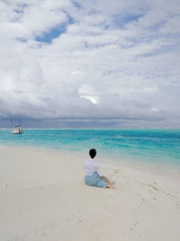 Rear view of woman sitting on beach