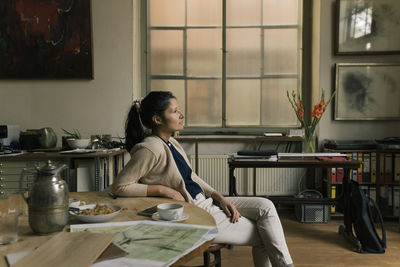 Contemplative businesswoman sitting by dining table in home office