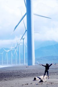 Rear view of woman standing against windmills 