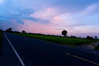 Empty road against sky at sunset