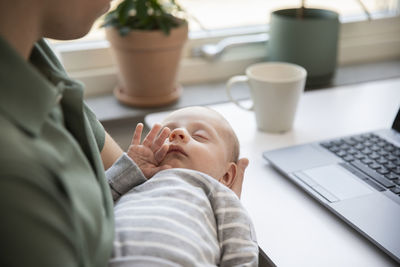 Father holding baby son and working from home