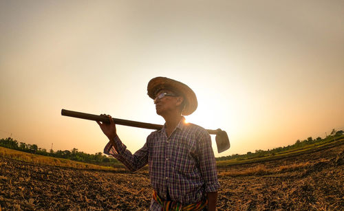 Man on field against sky during sunset