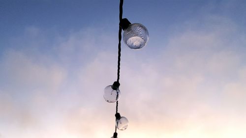 Low angle view of wet light bulbs against sky during sunset