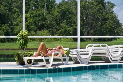 Woman relaxing in swimming pool against trees