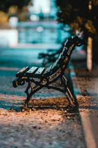 Close-up of empty bench on street