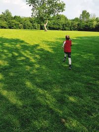 Rear view of boy running on grass