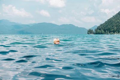 Boy with blond hair swimming in lake