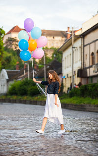Full length of woman standing with balloons in water