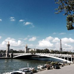 Bridge over river in city against cloudy sky