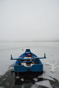 Boat moored on sea against sky during winter