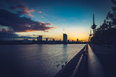 View of river and buildings against sky during sunset