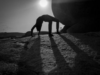 Side view of silhouette man doing yoga asanas on sunny day