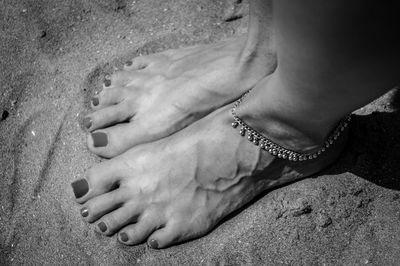 Low section of woman standing on sand