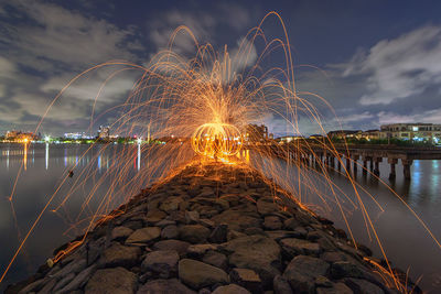 Firework display over river against sky at night