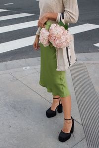 Full length of woman standing on street with pink flowers 