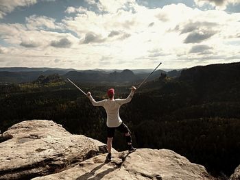 Rear view of woman standing on rock against sky