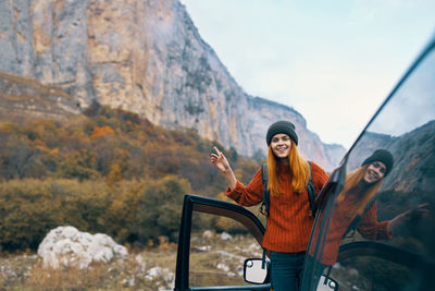 Young woman standing against mountain range