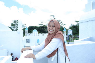 Portrait of smiling young woman against sky