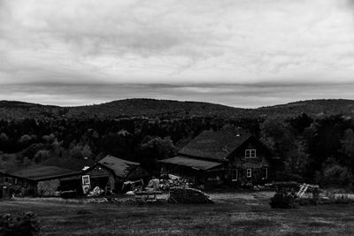 Houses on field against cloudy sky